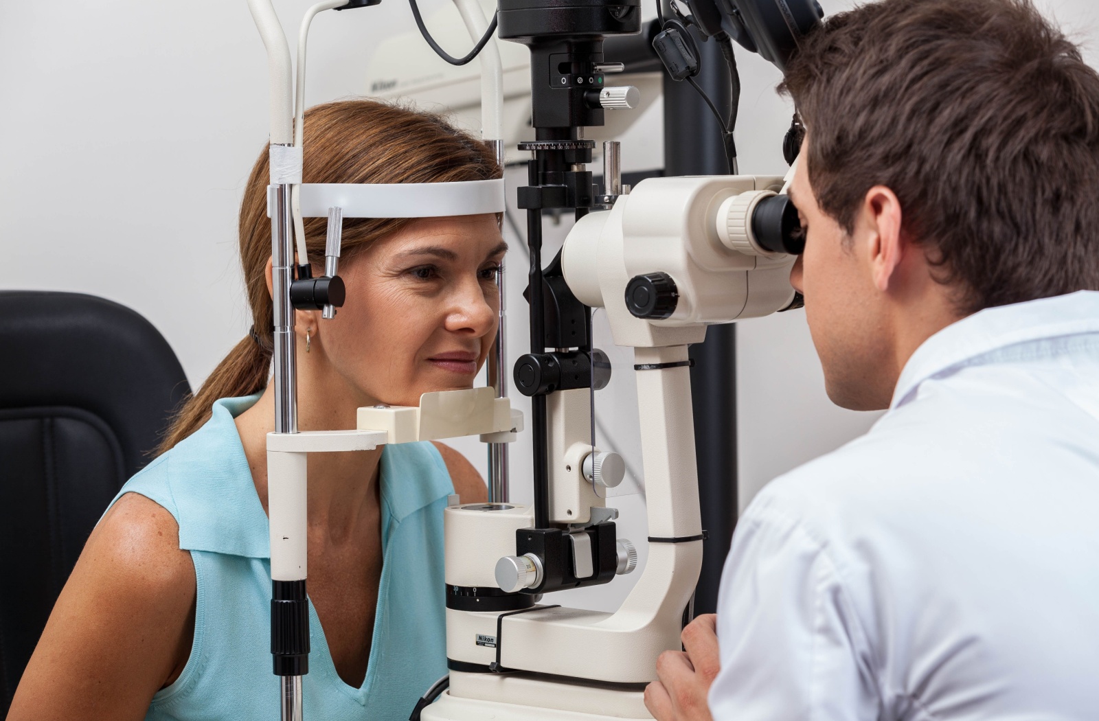 Optometrist performing an eye exam on female patient.