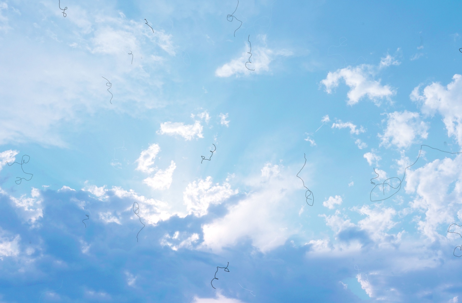 An image of a blue, cloudy sky with tiny black lines, demonstrating what floaters can look like in your vision.