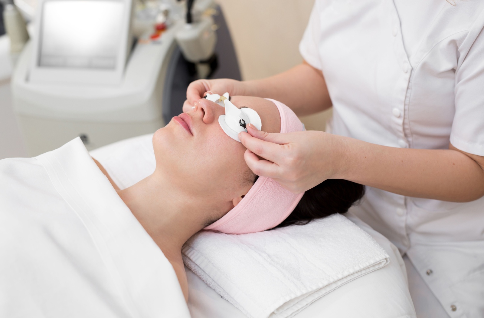 A clinician prepares a patient for IPL by fitting them with eye protection.